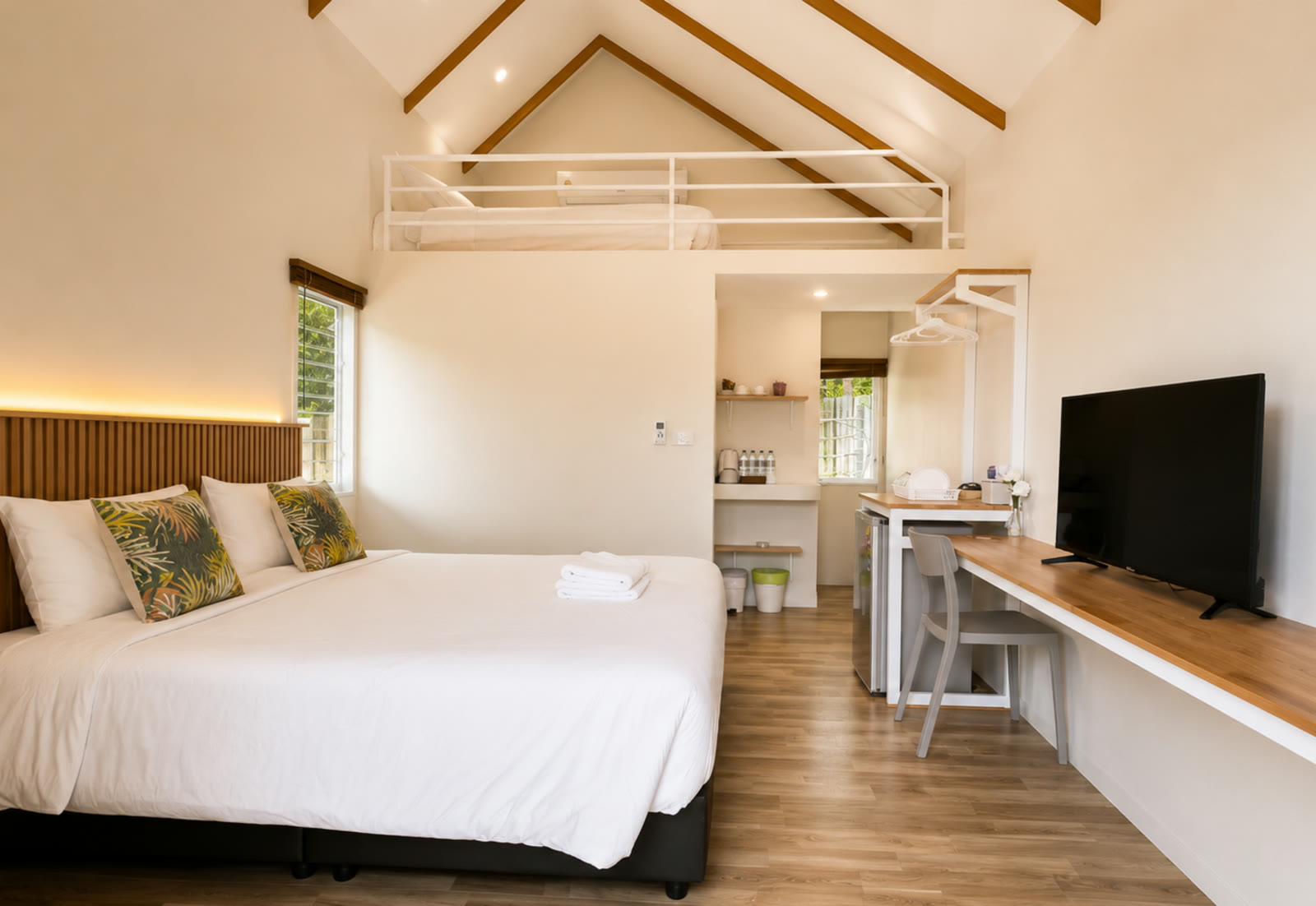 One-bedroom A-frame cabin interior at NaraRin Phuket — king bed under a vaulted ceiling with mezzanine loft